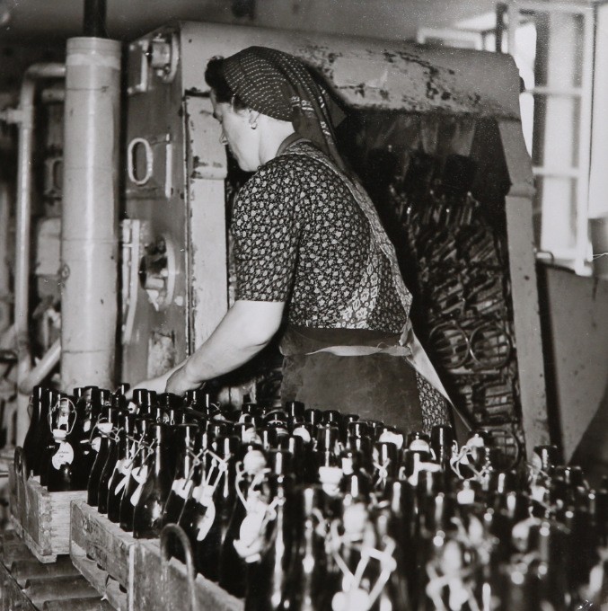 Ein Mitarbeiterin reinigt leere Bierflaschen vor der Abfüllung. Im Jahr 1939 war dieser Vorgang noch reine Handarbeit.