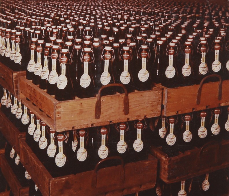 Bier in Bügelflaschen in Holzkästen. Die Aufnahme aus den 50er Jahren zeigt das ehemaligen Bierlager.
